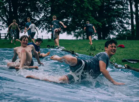 FLUX 3 clip: teenage boys sliding down a wet plastic tarp on a lawn