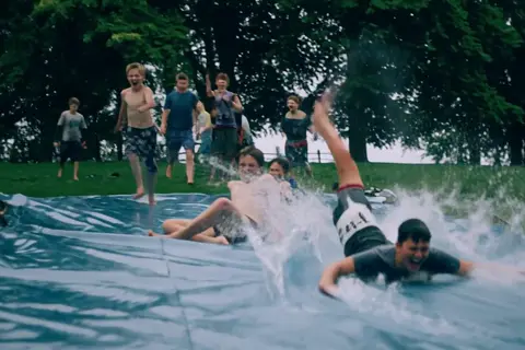 Hailuo H3 clip: teenage boys sliding down a wet plastic tarp on a lawn
