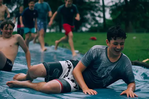 Happy Horse 1.1 clip: teenage boys sliding down a wet plastic tarp on a lawn