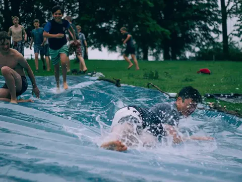 Luma Ray 3.2 clip: teenage boys sliding down a wet plastic tarp on a lawn