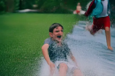 Pika 2.2 clip: teenage boys sliding down a wet plastic tarp on a lawn