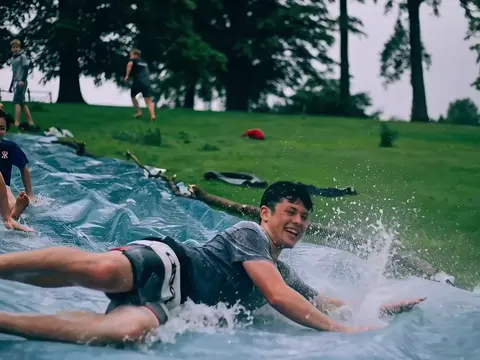 Seedance 2.0 clip: teenage boys sliding down a wet plastic tarp on a lawn