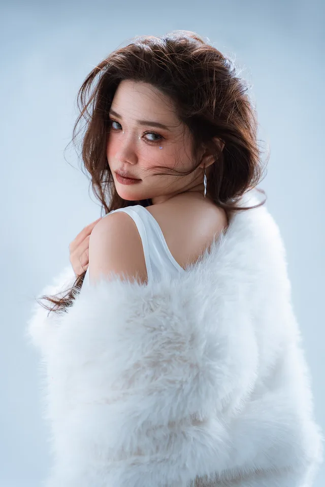 Studio portrait of a woman in a white fur wrap looking back over her shoulder
