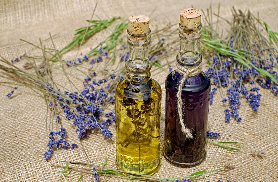 Two corked glass bottles of lavender oil on burlap with lavender stems
